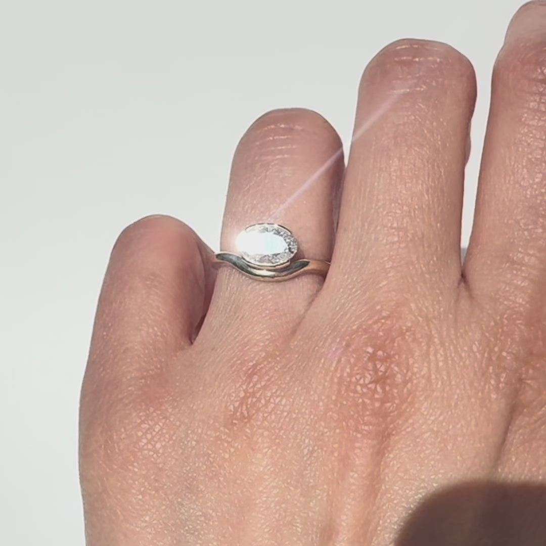 The Flow Ring features a 1 carat oval diamond or moissanite in a half bezel setting. The east west design adds a unique touch to this minimalistic design, making it the perfect subtle statement ring.