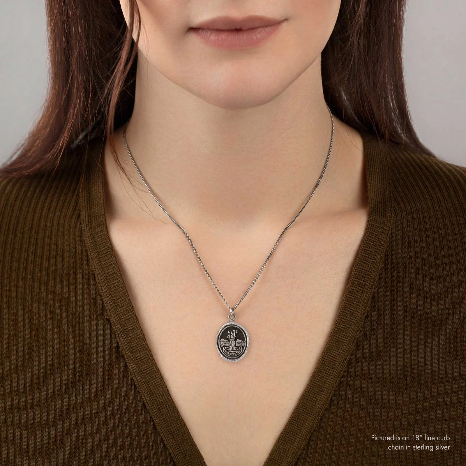 Woman wearing a silver necklace with a pendant against a neutral background